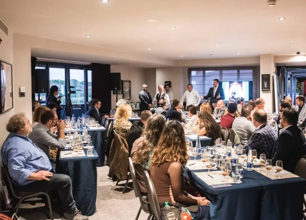 Pubblico seduto ai tavoli durante un evento aziendale in sala