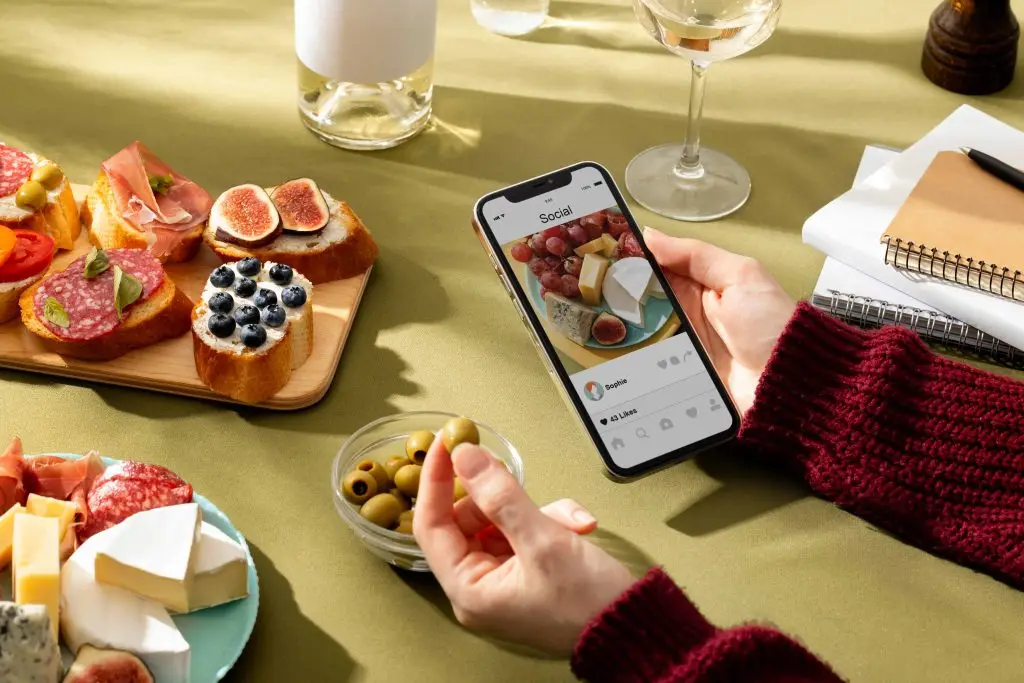 Tavola con taglieri e piatti e una mano che consulta lo smartphone