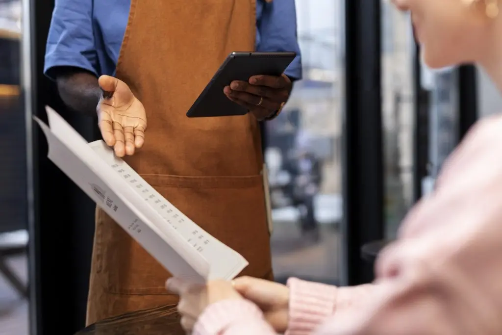 Cameriere con tablet che prende l'ordine di una cliente al ristorante